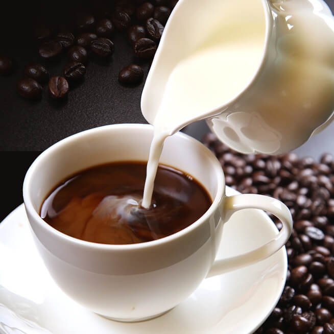 白いカップに注がれるコーヒーとミルク